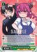 A Japanese trading card from Bushiroad's Of Age Duo, Iruru & Taketo Aida [Miss Kobayashi's Dragon Maid] showcases an anime-style illustration of a nervous boy with short black hair and a sweating face, standing next to a busty girl with long purple hair, pink horns, and a confident smile. The backdrop is pink with heart patterns. The card's green border displays game stats and text in Japanese—making it a truly rare Character Card.