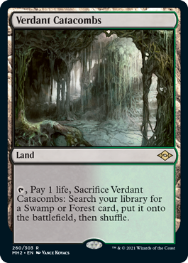 A Magic: The Gathering product titled "Verdant Catacombs [Modern Horizons 2]" from Magic: The Gathering. This Land card lets you pay 1 life and sacrifice it to search for a Swamp or Forest to put onto the battlefield. The artwork depicts a dark, overgrown, cavernous forest, with full details and artist credit on the card.