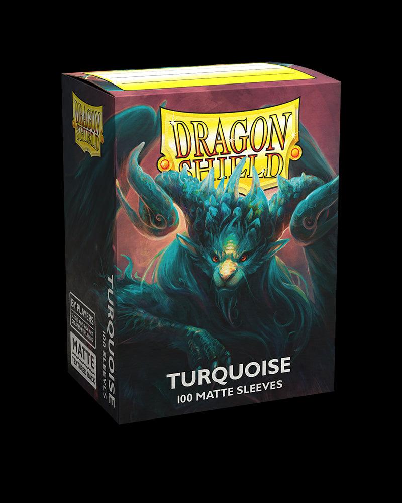 A product image of Arcane Tinmen brand trading card sleeves. The box is predominantly turquoise and features an artwork of a fierce, mystical dragon with horns and large wings. The text on the box reads "Dragon Shield: Standard 100ct Sleeves - Turquoise (Matte)". The box stands against a black background.