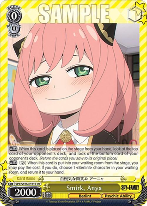 A trading card features Anya Forger from the anime "SPY x FAMILY" with a mischievous smirk. She has pink hair and green eyes, and wears a school uniform with a black and gold dress and a white bow tie. The promo card **Smirk, Anya (SPY/S106-E101S PR) [SPY x FAMILY]** by **Bushiroad** showcases her psychic ability, Japanese text, and stats, including a power level of 2000.