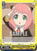 A trading card Okey-Dokey, Anya (SPY/S106-TE04R RRR) [SPY x FAMILY] by Bushiroad features Anya from "Spy x Family." She wears a black and yellow outfit with a red tie, has light pink hair, large green eyes, and salutes with a serious expression. The card displays various stats, including her psychic ability with a power level of 2500, detailing in-play abilities.