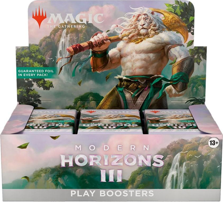 A display box for "Magic: The Gathering" Modern Horizons 3 - Play Booster Display, featuring an illustration of a powerful lion-like creature wielding a large sword. Text on the box promises a guaranteed foil in every pack. The box holds booster packs set against a vibrant landscape background.