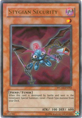 The "Yu-Gi-Oh!" trading card titled "Stygian Security [WC10-EN002] Ultra Rare" features an illustration of a small, blue creature with bat-like wings and metallic claws, set against a dark, swirling background. This ultra rare Fiend-Type Tuner Monster has 100 ATK and 600 DEF, with text and stats clearly visible.