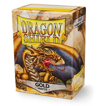 A box of Dragon Shield: Standard 100ct Sleeves - Gold (Matte) by Arcane Tinmen. The packaging features artwork of a fierce, golden dragon with a long red tongue against a rocky backdrop. Promising 100 durable matte gold card sleeves, the box proudly displays the prominent Dragon Shield logo near the top.