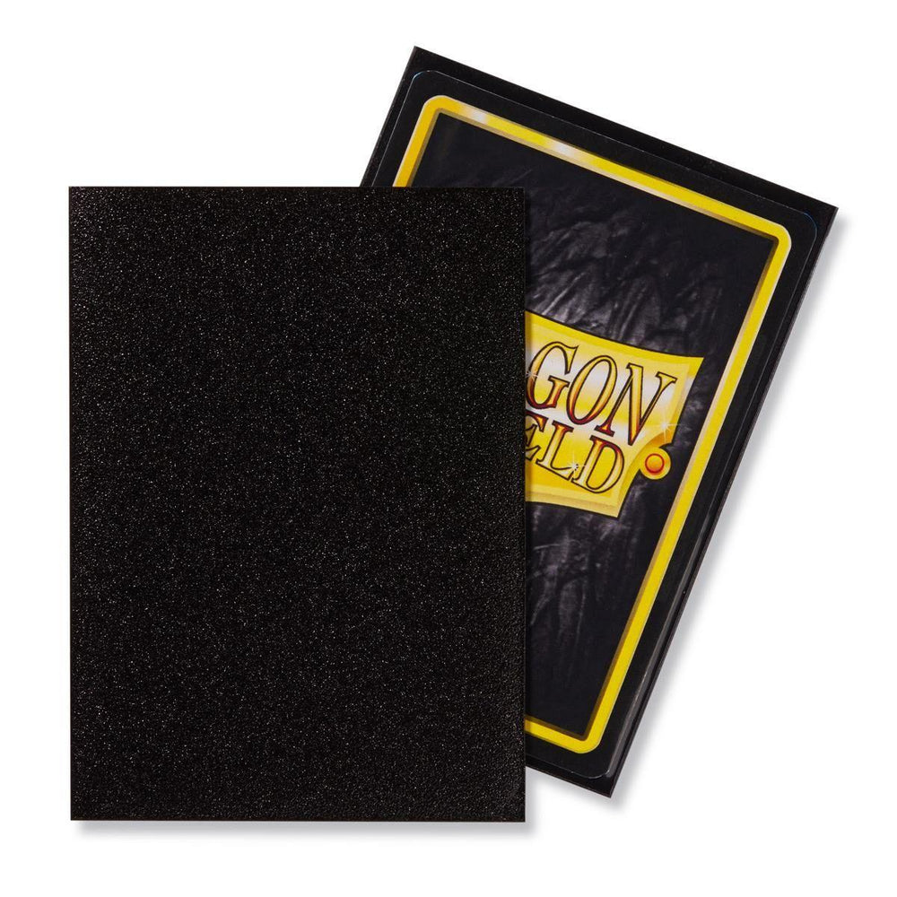 In the foreground, there's a black textured card from the Dragon Shield: Standard 100ct Sleeves - Jet (Matte) by Arcane Tinmen, partially covering another card adorned with a yellow-bordered design and the words "Dragon Shield." Both cards, edged with a sleek black frame, provide durable protection as high-quality card sleeves.