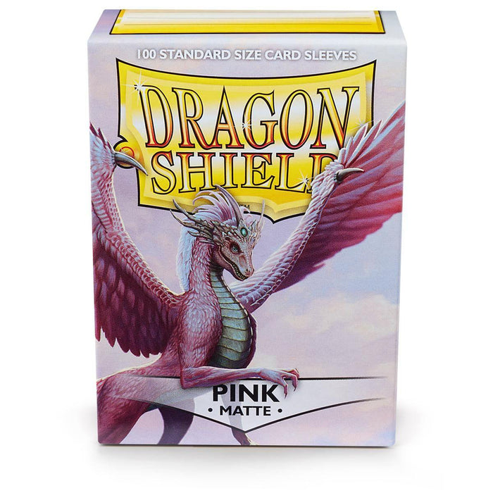 A box of Arcane Tinmen Dragon Shield: Standard 100ct Sleeves - Pink (Matte) is shown, featuring a majestic dragon illustration. The dragon has pink scales, large wings, and a fierce expression, with the text "DRAGON SHIELD" in a gold banner and "100 Standard Size Matte Card Sleeves PINK MATTE" at the bottom.