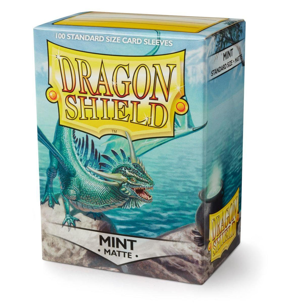 Arcane Tinmen's Dragon Shield: Standard 100ct Sleeves - Mint (Matte) showcases a vibrant green dragon on a rocky ledge by water. The eye-catching design emphasizes the fantasy theme.