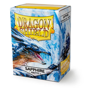 A box of Arcane Tinmen Dragon Shield: Standard 100ct Sleeves - Sapphire (Matte). The packaging features an illustration of a blue dragon with icy detailing. The box advertises "100 Standard Size Card Sleeves" and has bold yellow and white branding with the words "Dragon Shield" prominently displayed.