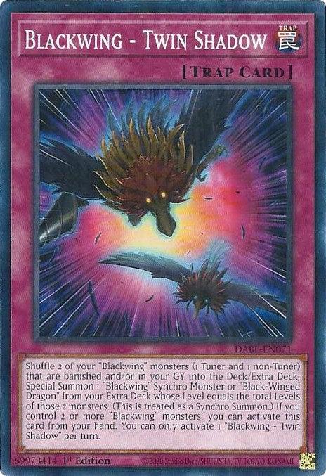 The Yu-Gi-Oh! card "Blackwing - Twin Shadow [DABL-EN071]" is a Common Trap card. It features a purple border and an illustration of two winged creatures enveloped by swirling energy. Below the image, the card text explains its effect: shuffling two Blackwing monsters to execute a Synchro Summon of a formidable Blackwing Synchro Monster.