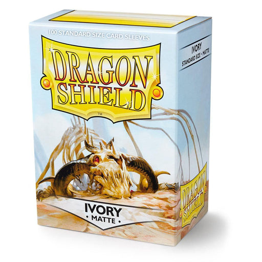 A box of Arcane Tinmen Dragon Shield: Standard 100ct Sleeves - Ivory (Matte) with a dragon skull illustration on the front. The text "100 STANDARD SIZE CARD SLEEVES" is at the top, and "DRAGON SHIELD" is prominently displayed in the center. Featuring an "IVORY MATTE" finish, these card sleeves are praised for their durability.