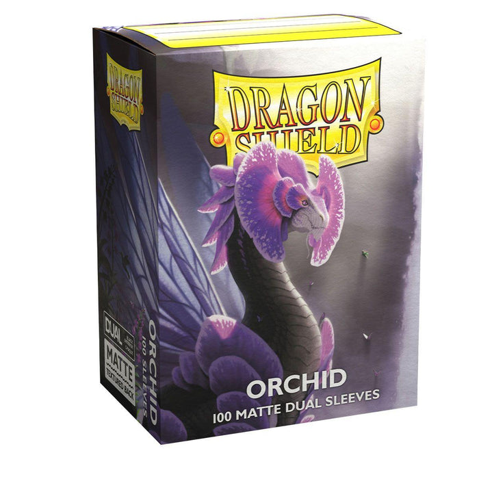 A box of Arcane Tinmen Dragon Shield: Standard 100ct Sleeves - Orchid (Dual Matte) with "Orchid" written on it. The 100 matte dual sleeves come in a package showcasing a black dragon with purple flowers and wings, surrounded by orchid flowers. The dragon, poised on the front, has light purple eyes that add to the enchanting design.