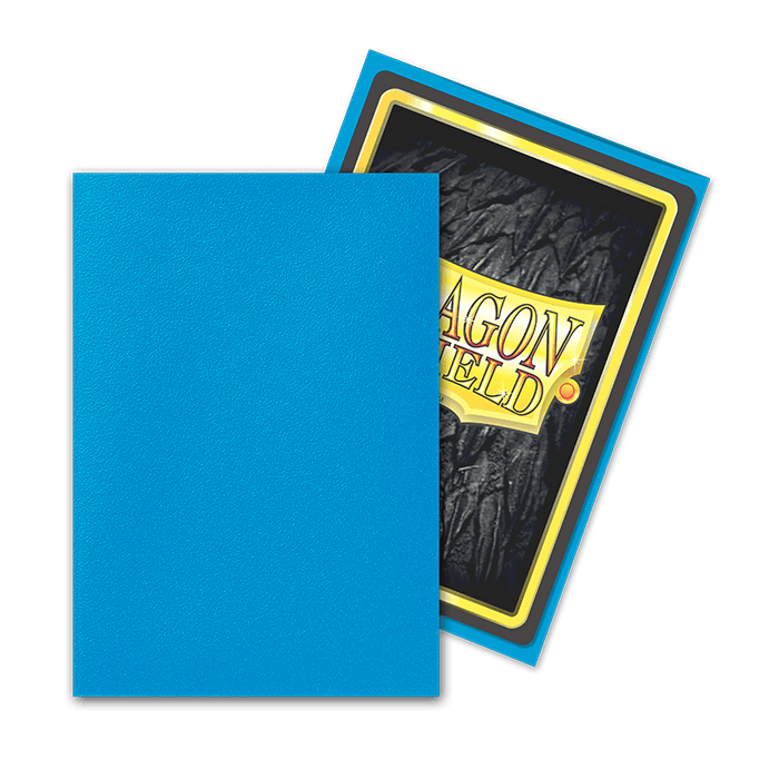 Two card sleeves are shown. The sleeve on the left is a plain blue from the Dragon Shield: Japanese Size 60ct Sleeves - Sapphire (Matte) by Arcane Tinmen. The sleeve on the right displays the back of a card, partially obscured by the blue sleeve. The card back features a black textured background with a yellow border and a partial view of the "Dragon Shield" logo, perfect for TCGs using these Japanese size sleeves.