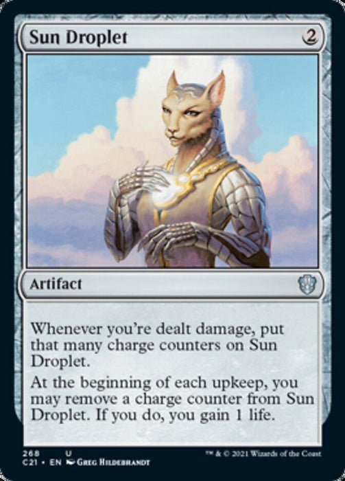 A Magic: The Gathering product titled "Sun Droplet [Commander 2021]" is an artifact from Magic: The Gathering. It features a humanoid cat-like creature holding a glowing, sun-like orb in its chest. Costing 2 generic mana, it has abilities to gain life when damage is dealt and to remove charge counters.
