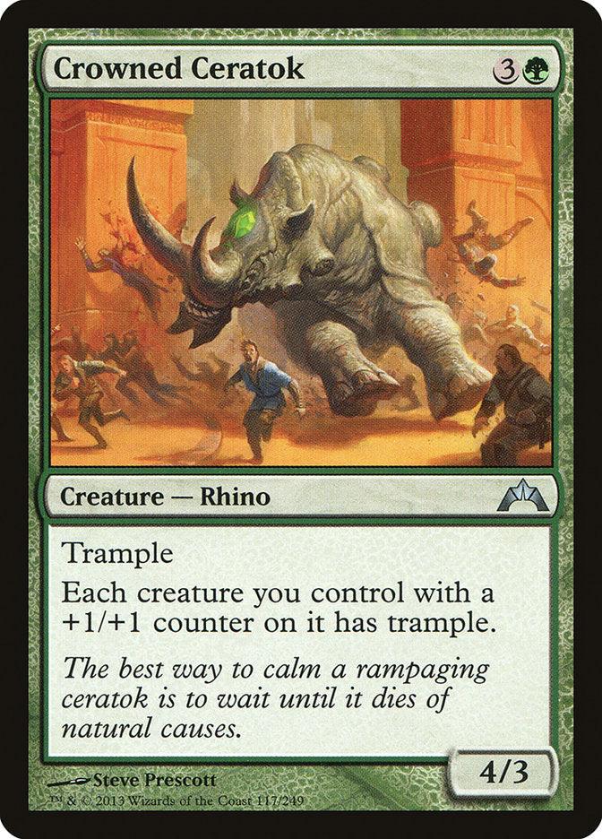 A Magic: The Gathering card named Crowned Ceratok [Gatecrash] from the Gatecrash set features an illustration of a large, armored Rhino with a glowing green crown-like structure on its head, charging through a group. The card's abilities include Trample and granting trample to each creature you control with a +1/+1 counter. It has stats 4/3 and costs 3 generic.