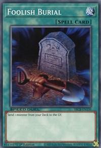 Image of a "Yu-Gi-Oh!" trading card titled "Foolish Burial [SBCB-EN139] Common." The Normal Spell card shows an eerie graveyard scene with a tombstone and a shovel in the foreground. It's labeled as a Spell Card with the effect "Send 1 monster from your Deck to the GY.