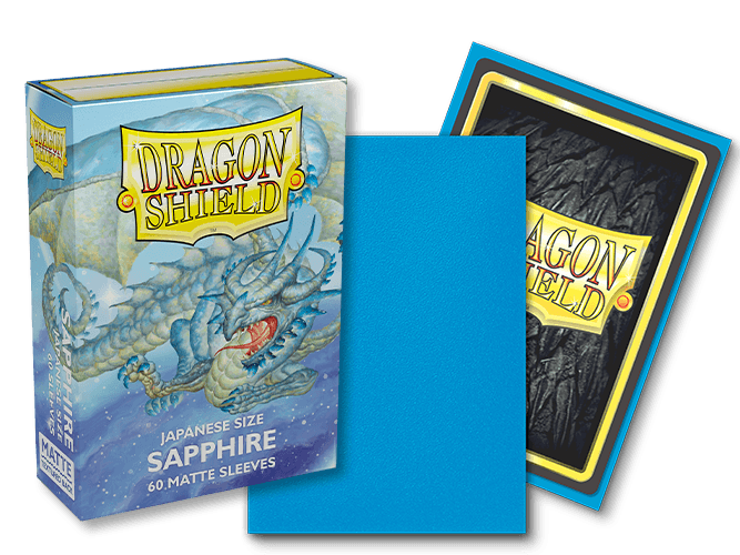 Image of the Arcane Tinmen Dragon Shield: Japanese Size 60ct Sleeves - Sapphire (Matte) product. The packaging displays an illustration of a blue dragon and reads "DRAGON SHIELD" along with "Japanese Size," "Sapphire," and "60 Matte Sleeves." A single blue sleeve is pictured standing against the box, ideal for TCGs, with its reverse side visible in the background.