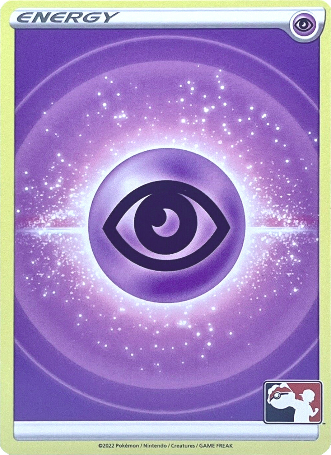 The Pokémon Psychic Energy card from the Prize Pack Series Two displays a captivating design, highlighted by a central eye symbol amidst a radiant energy field adorned with sparkles, all set against a gradient purple backdrop. The card features the word 