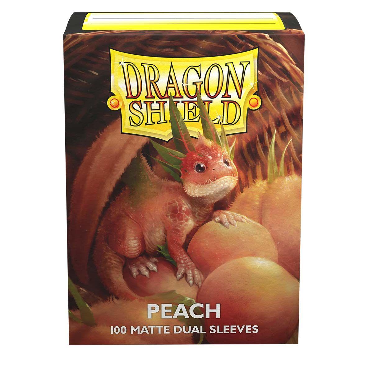 The image shows a sturdy cardboard box of Arcane Tinmen Dragon Shield: Standard 100ct Sleeves - Peach (Dual Matte). The front features an illustration of a small, red-orange dragon with green leafy protrusions on its head, sitting among peaches. The text on the box reads 