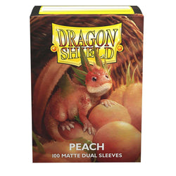 The image shows a sturdy cardboard box of Arcane Tinmen Dragon Shield: Standard 100ct Sleeves - Peach (Dual Matte). The front features an illustration of a small, red-orange dragon with green leafy protrusions on its head, sitting among peaches. The text on the box reads "Dragon Shield" and "Peach 100 Matte Dual Sleeves" with a black interior visible through the window.