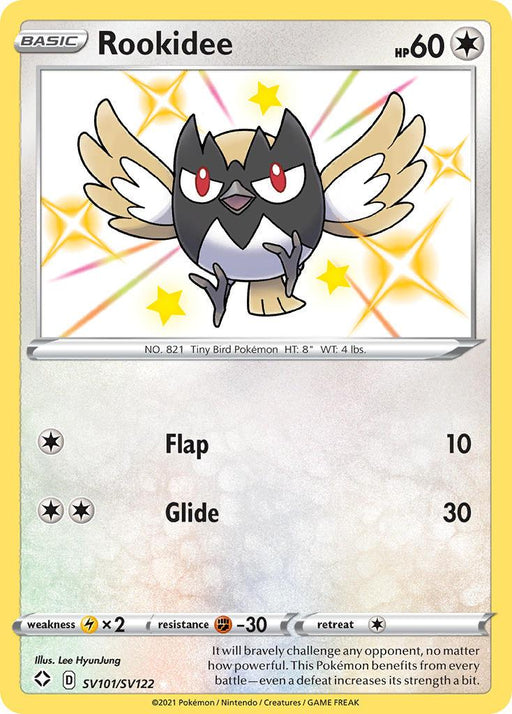 A Pokémon trading card featuring Rookidee (SV101/SV122) [Sword & Shield: Shining Fates], the Tiny Bird Pokémon from the Shining Fates series. Rookidee, a small bird, is depicted with a black head, yellow and red beak, large eyes with white wings tipped in black. This Colorless Ultra Rare card includes Rookidee's stats and moves "Flap" (10 damage) and "Glide" (30 damage).

