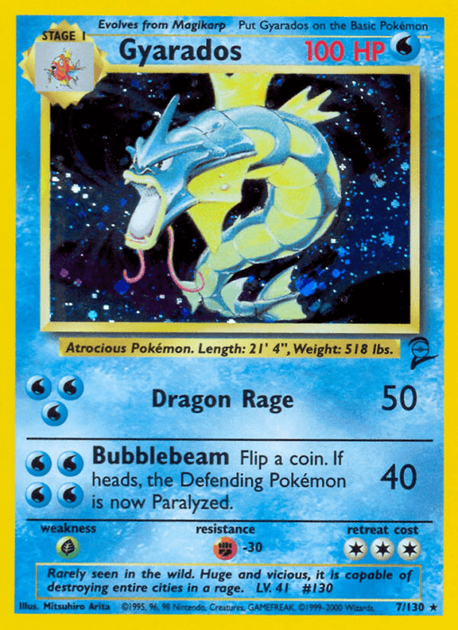 A Pokémon card for Gyarados (7/130) [Base Set 2] from Pokémon, featuring a large blue and yellow dragon-like creature with an open mouth and sharp teeth. This Holo Rare card showcases 100 HP (hit points) and includes two attacks: "Dragon Rage" with 50 damage and "Bubblebeam" with 40 damage, alongside a coin flip to paralyze the opponent.