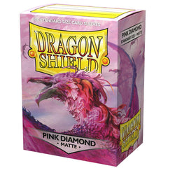 A box of Arcane Tinmen's Dragon Shield: Standard 100ct Sleeves - Pink Diamond (Matte), featuring a vibrant artwork of a pink and purple dragon with intricate feather-like scales. The packaging indicates it contains "100 Standard Size Card Sleeves.